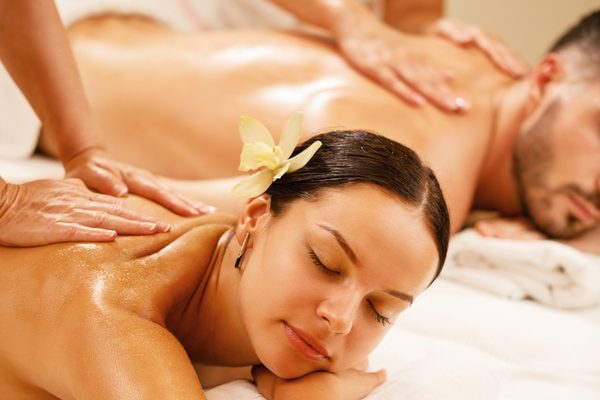 Young couple relaxing during back massage at health spa. Focus is on young woman.